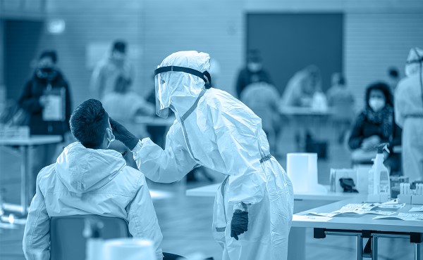 Public health worker in PPE administering a COVID test