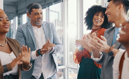 A diverse group of coworkers talks and laughs in an office