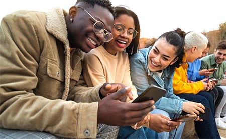 A young man shows something positive on his phone to friends