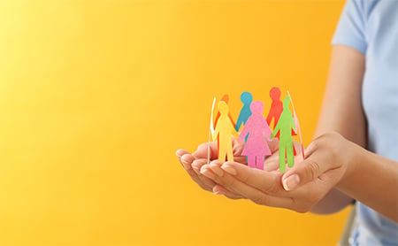 A pair of hands holds a multicolor paper chain in the shape of people holding hands