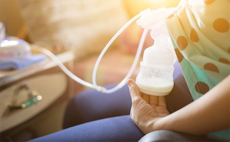 Midsection shot of a seated woman pumping breast milk